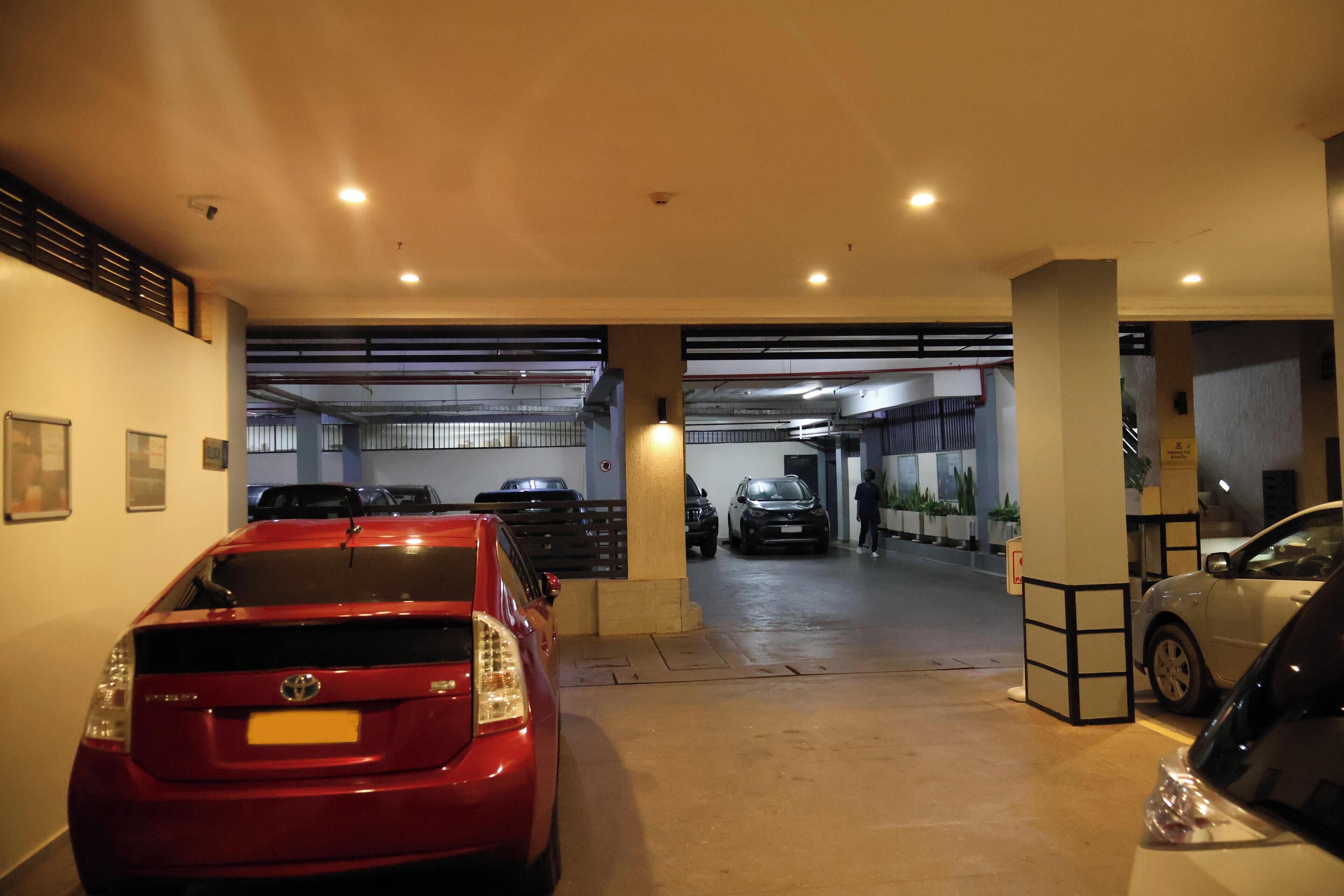 A parking garage with multiple cars, including a red Toyota and a silver sedan.