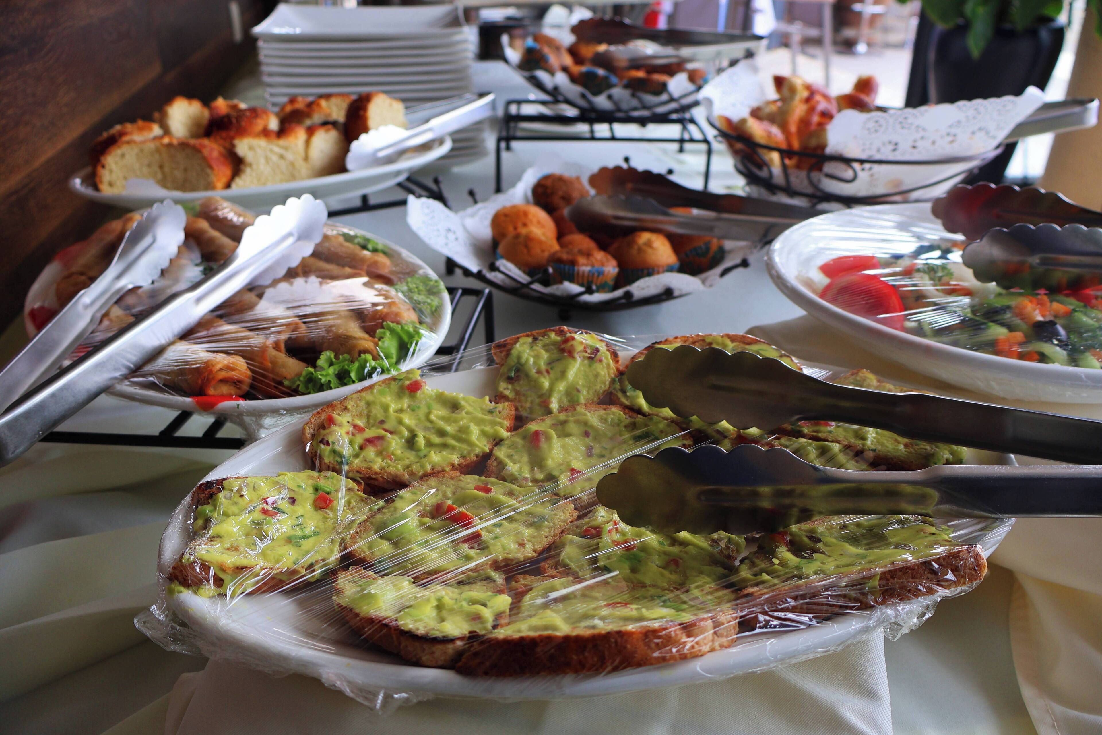 En buffet med forskellige retter, heriblandt brød, muffins og en salat.