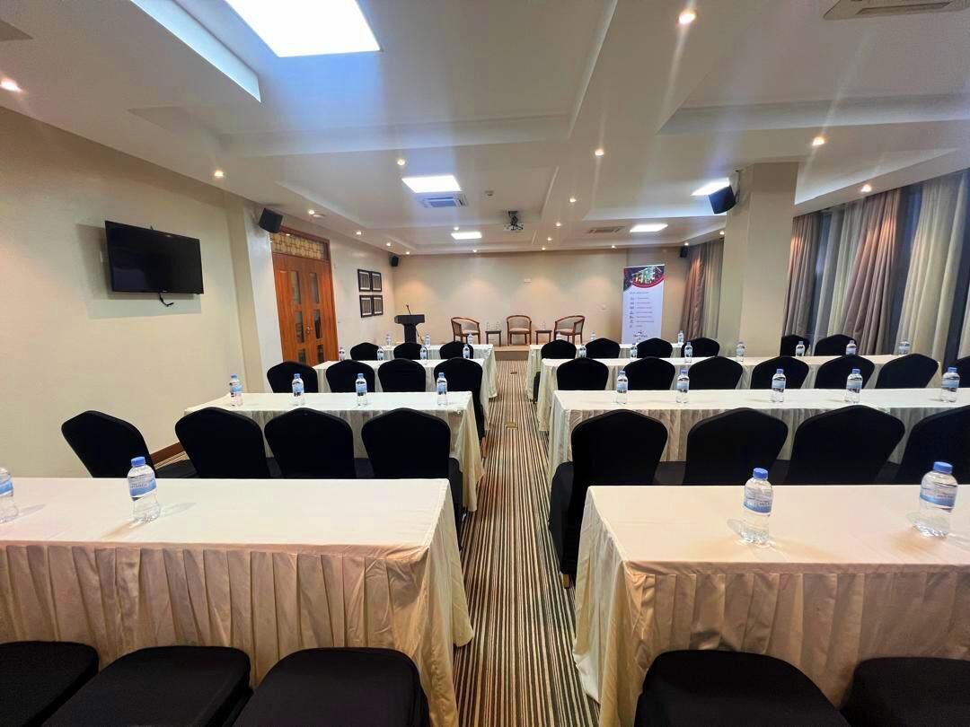 A conference room with tables and chairs, a flat-screen TV, and a podium.