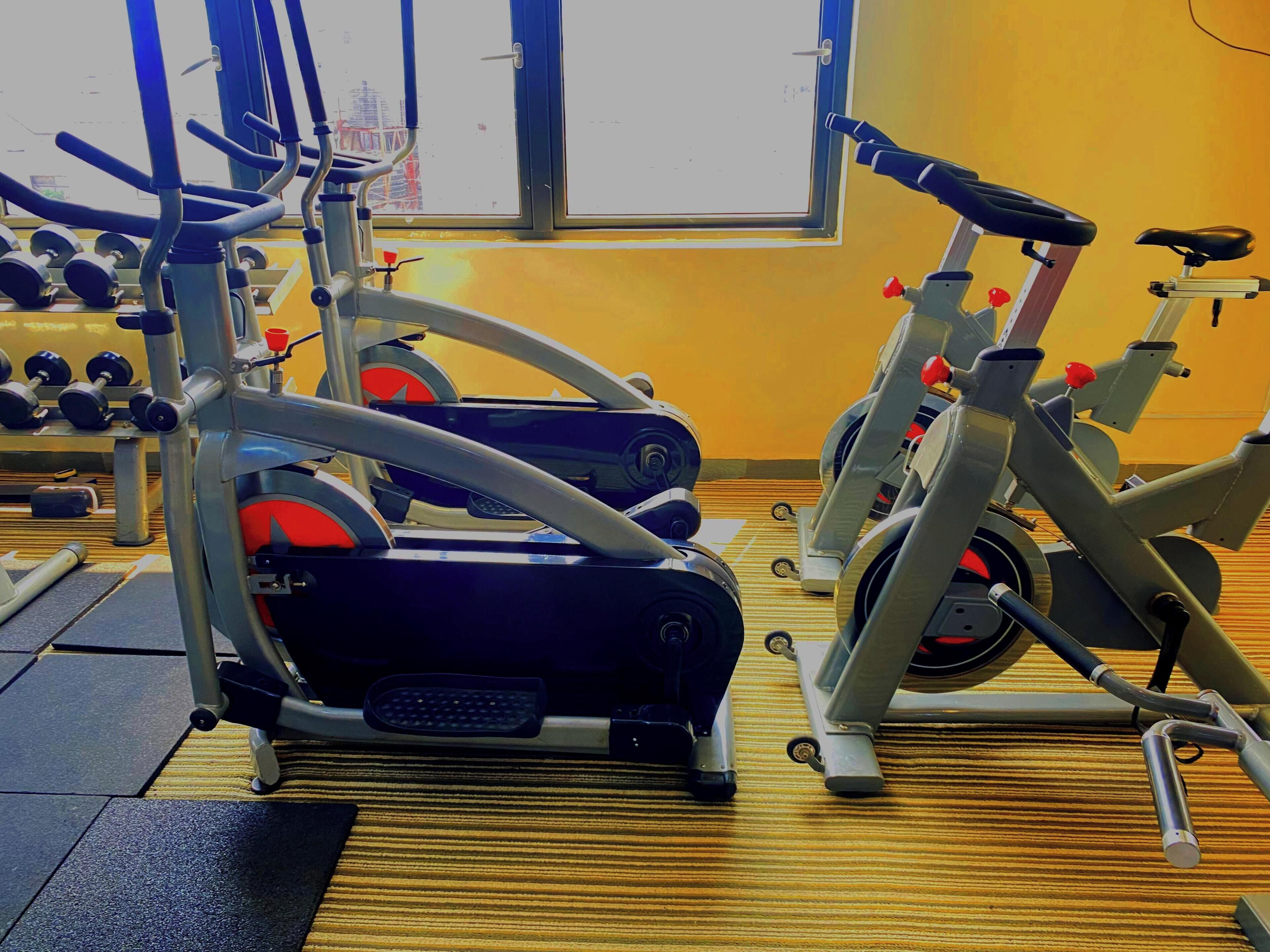 Et fitnesscenter med træningsudstyr, herunder løbebånd og håndvægte.