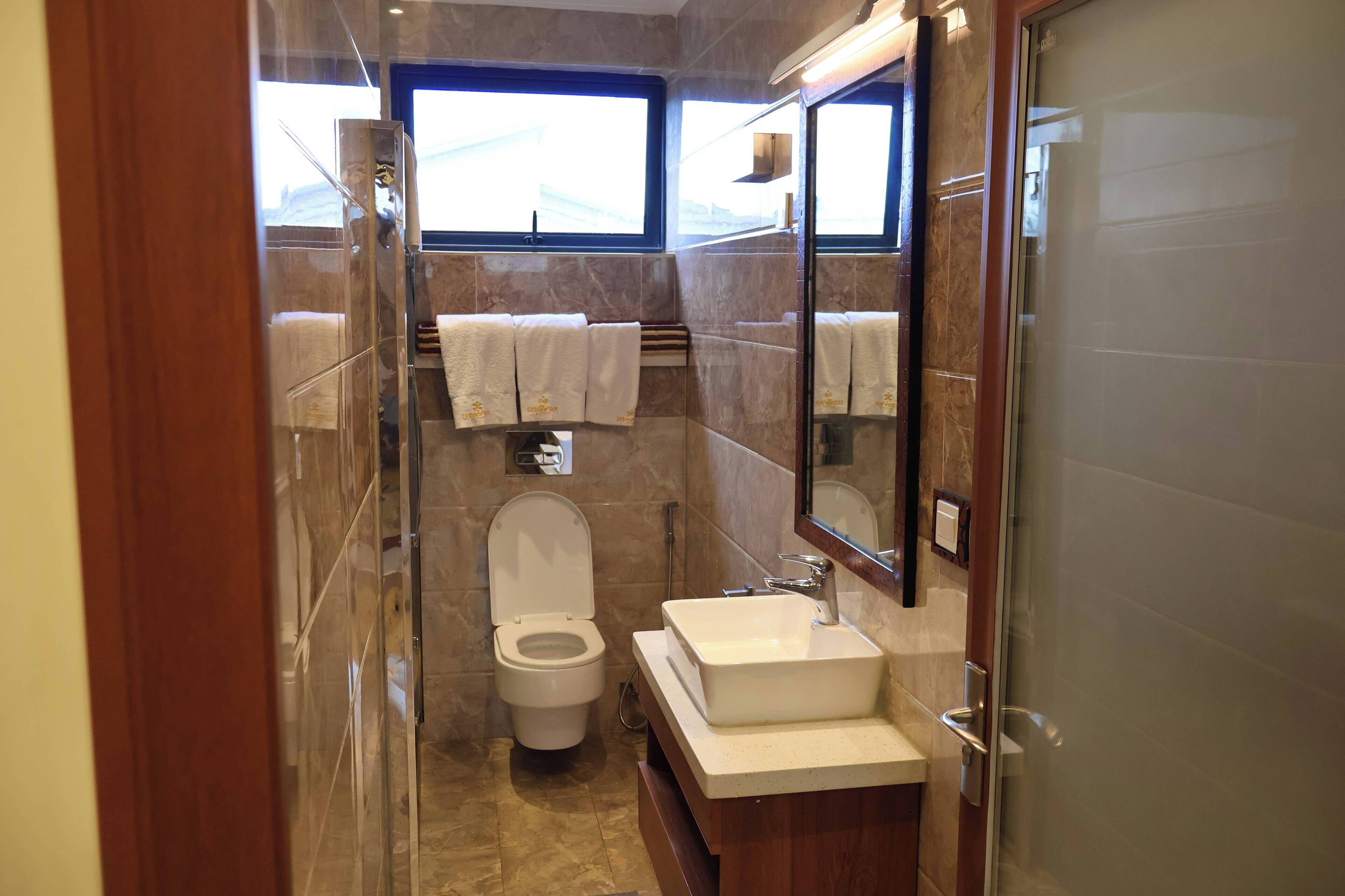 A compact bathroom with a toilet, sink, and large mirror.