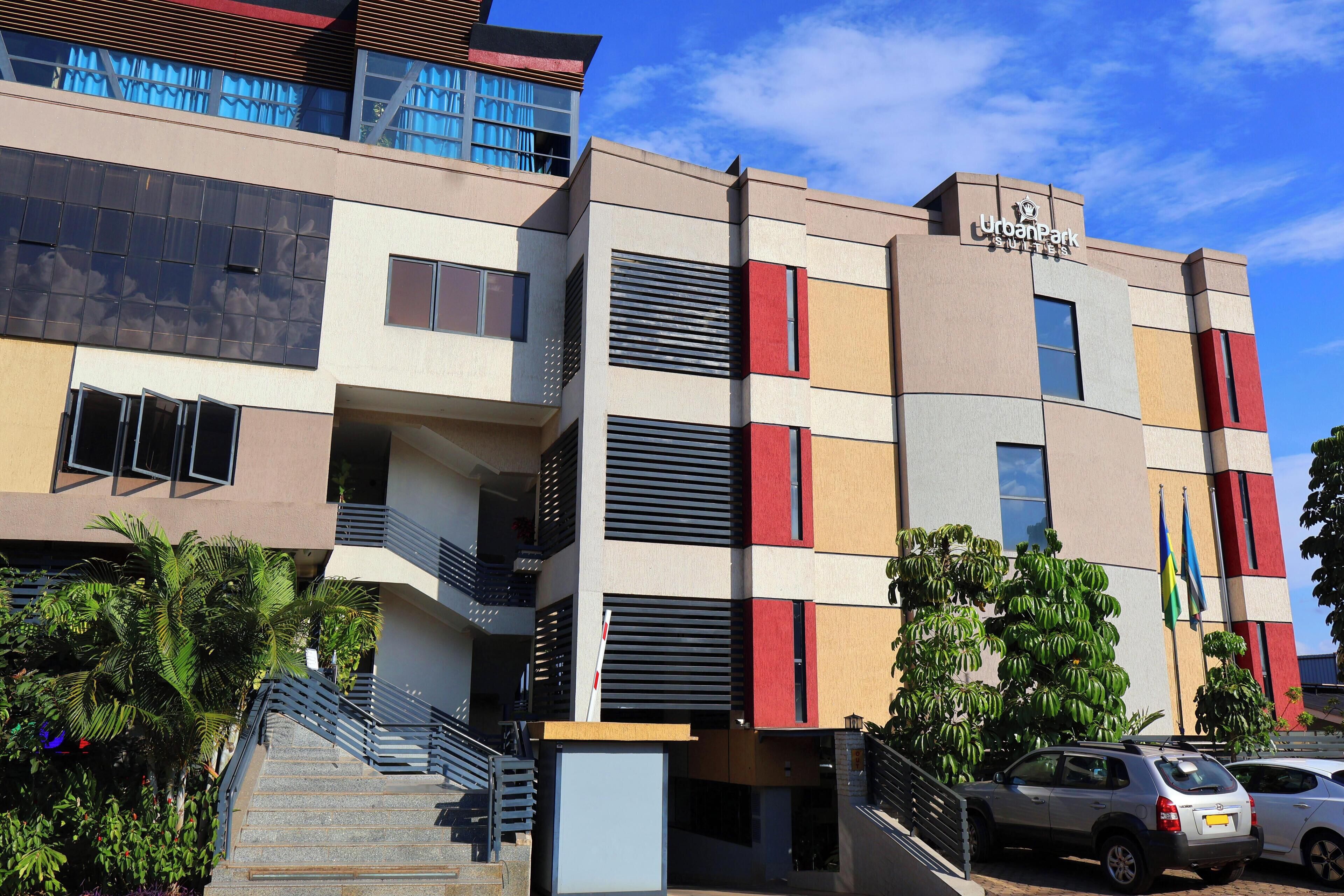 A multi-story hotel with balconies, a staircase, and parked cars.