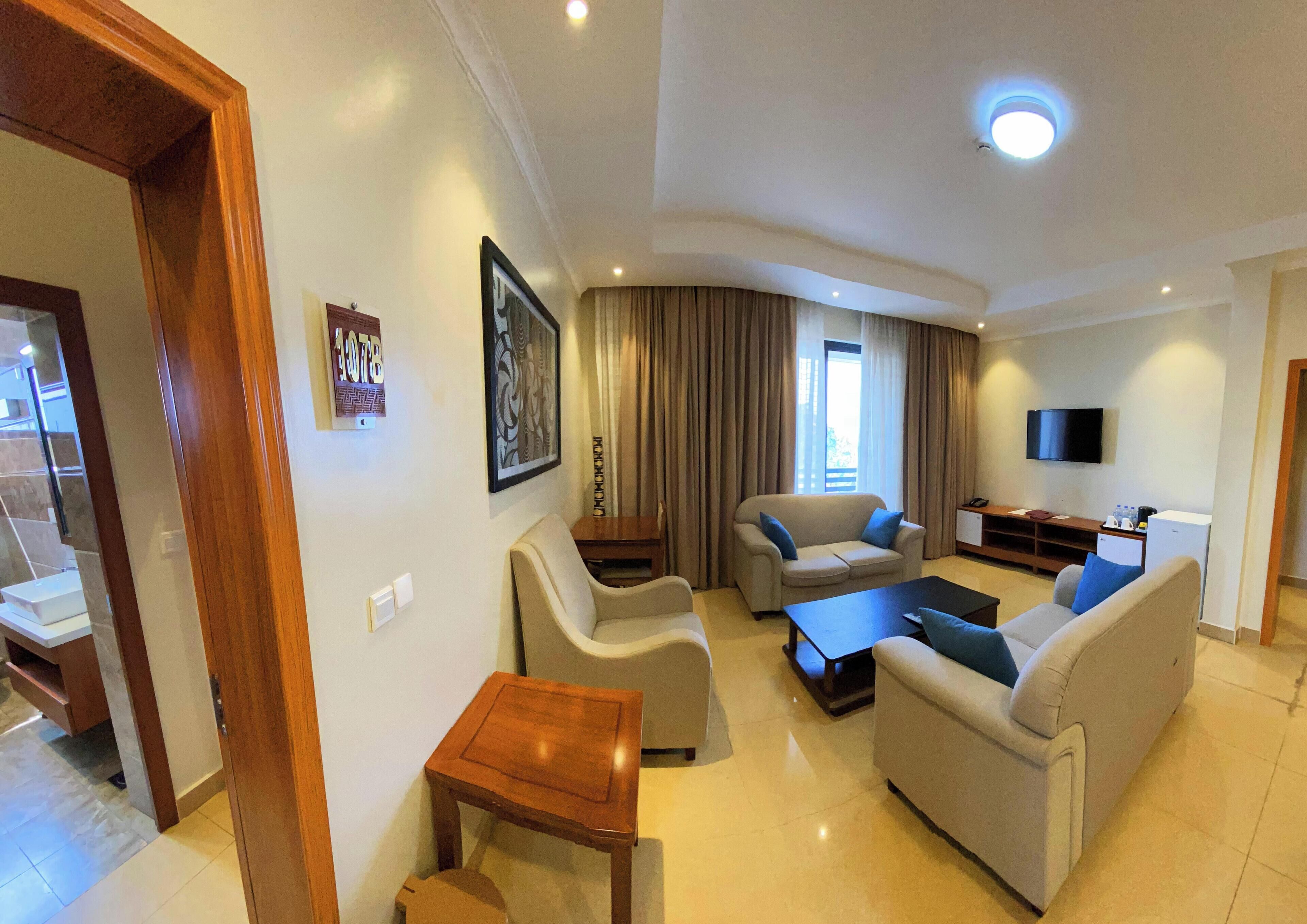 Una sala de estar moderna con un sofá, sillones, una mesa de centro y un televisor.