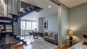 Un appartement moderne comprenant un escalier, un coin repas, un salon et une chambre.