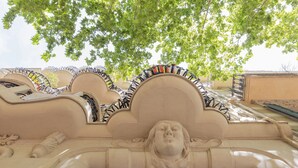 Detaljeret arkitektonisk skulptur med et udskåret ansigt, udsmykkede detaljer og et træ over hovedet.