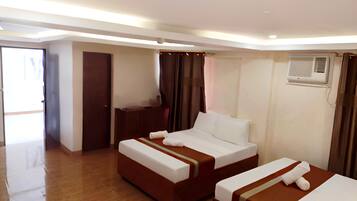 Habitación de hotel con dos camas, un escritorio y un equipo de aire acondicionado.