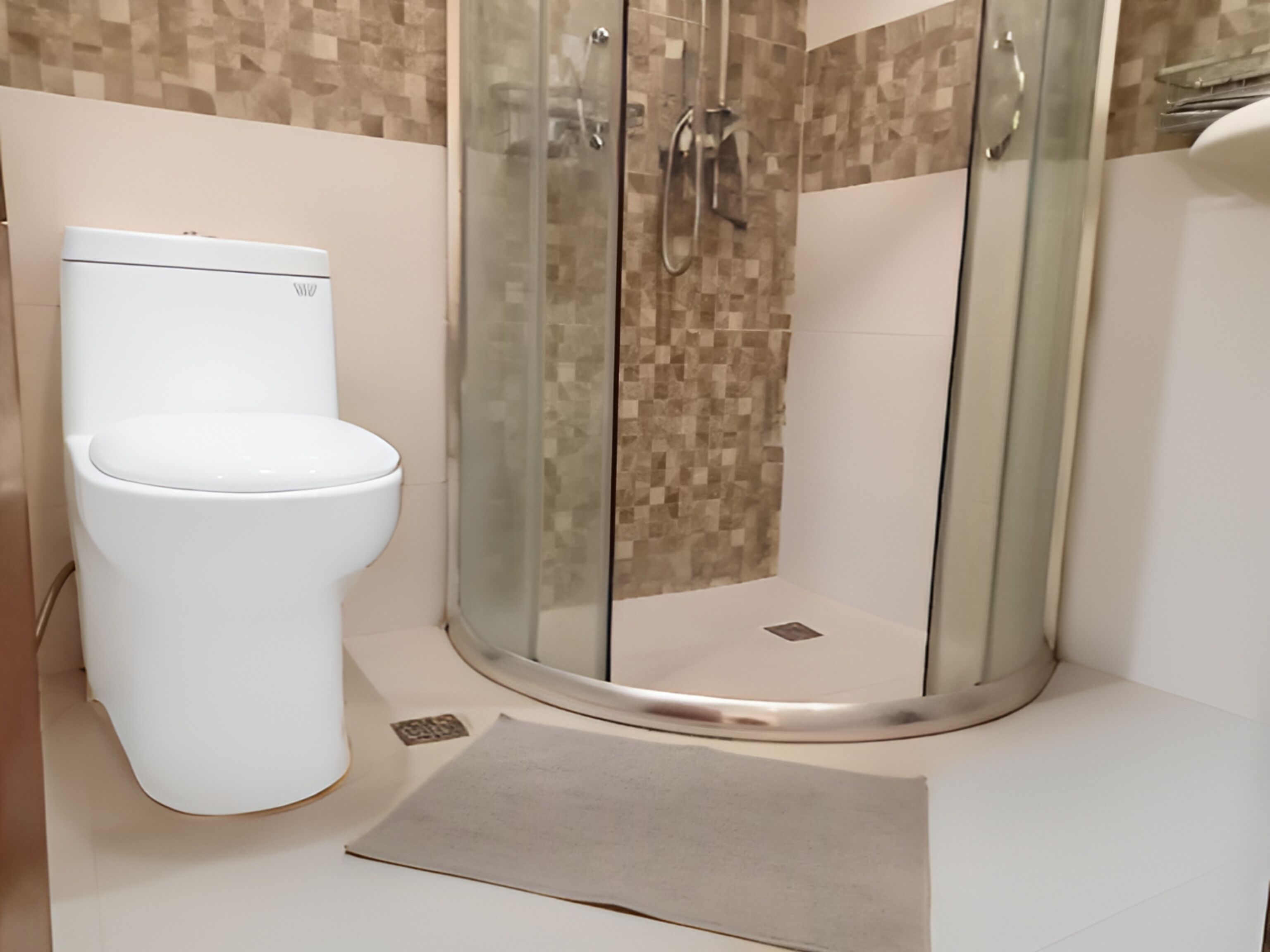 A modern bathroom with a toilet, a glass-enclosed shower, and a tiled wall.