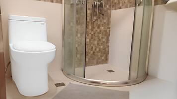 A modern bathroom with a toilet, a glass-enclosed shower, and a tiled wall.