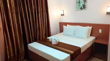 Ein Hotelzimmer mit einem Bett, einem Nachttisch, einem Vorhang und einer Wandleuchte.