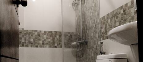 A bathroom with a glass-enclosed shower, a toilet, and a sink.