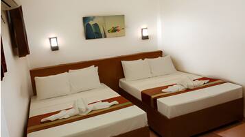 A hotel room with two single beds, a wooden headboard, white bedding, a painting on the wall, and two wall-mounted lights.