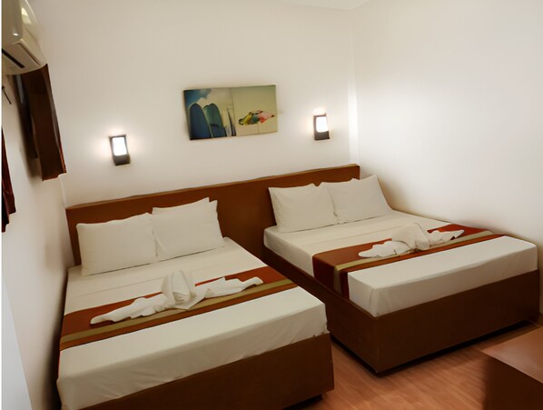 Habitación de hotel con dos camas individuales, cabecero de madera, ropa de cama blanca, un cuadro en la pared y dos lámparas de pared.