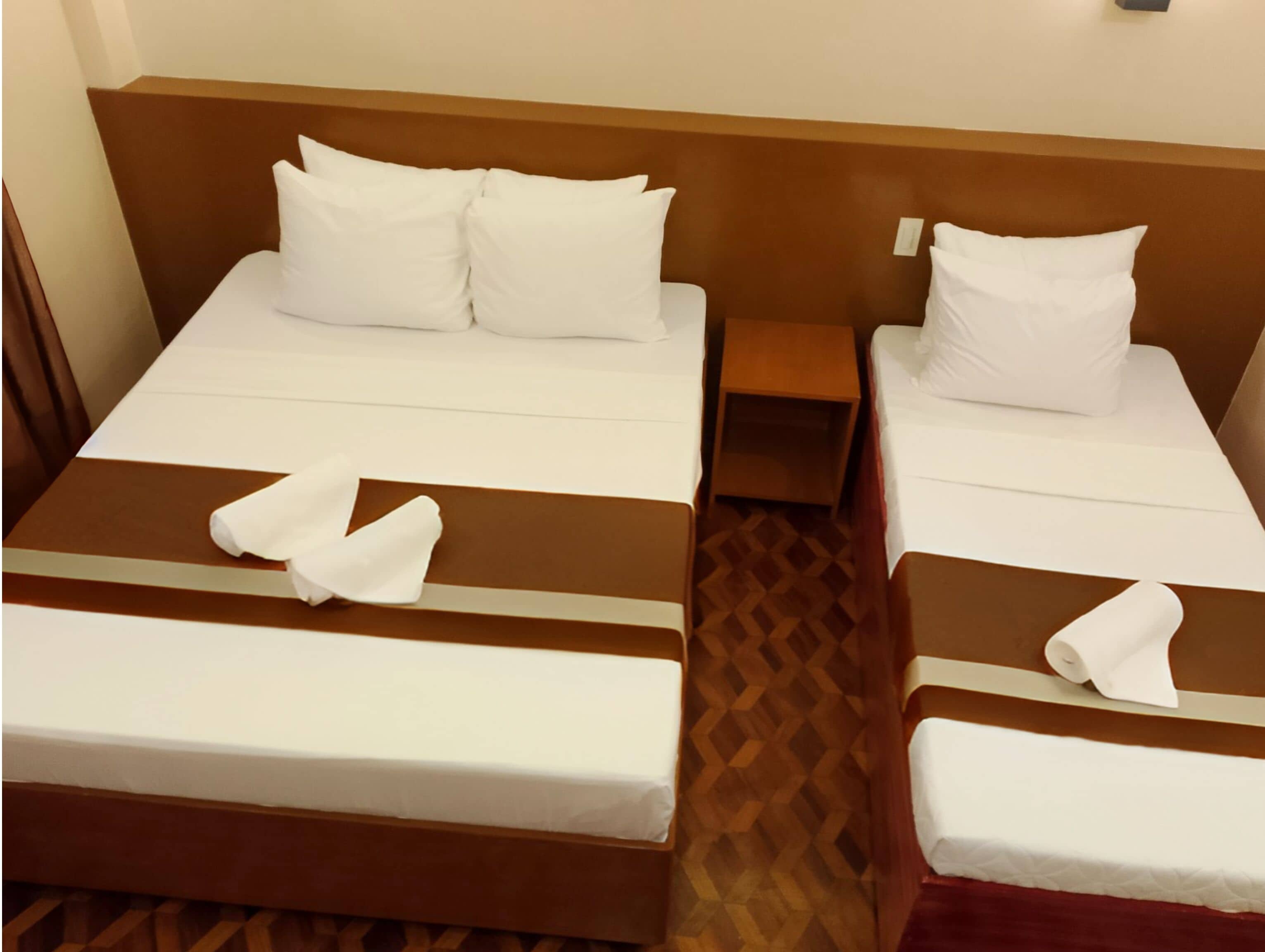 Two single beds with white linens and brown headboards in a hotel room.