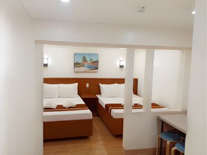 A hotel room with two beds, a painting on the wall, and a small table with chairs. - Dy Heritage Suites (Vigan)