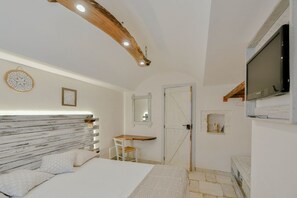 A bedroom with a wooden headboard, a bed, a desk, a television, and a mirror.
