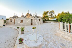 A courtyard with stone flooring, a white fence, and a building with multiple domed roofs.