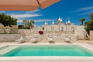 A pool area with lounge chairs and a view of a white building with multiple domes.