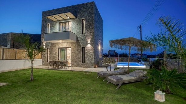 A modern two-story house with a swimming pool, outdoor seating, and a well-maintained lawn.