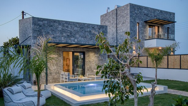 A modern house with a swimming pool, a patio with outdoor furniture, and a stone facade.