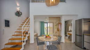 A modern kitchen with a stainless steel refrigerator, wooden staircase, and a dining area with a fruit bowl.