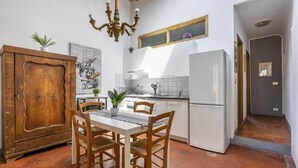 Een keuken met een eettafel, stoelen, een koelkast en een houten kast.