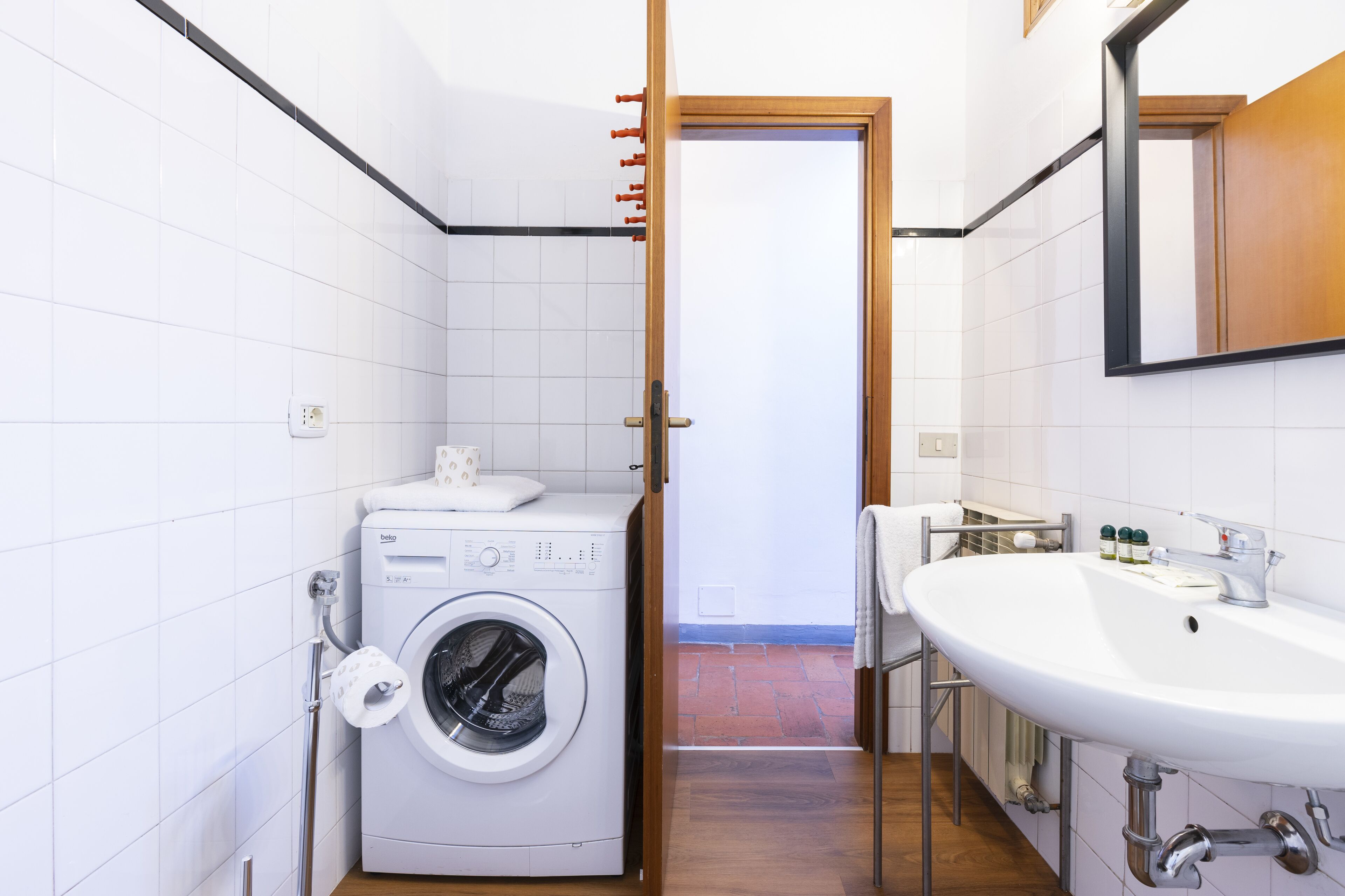 Un baño pequeño con lavadora, lavamanos y espejo.