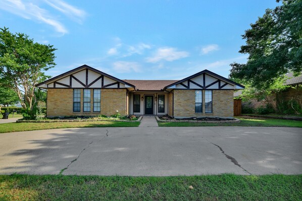 A two-story house with a symmetrical facade, a central entrance, and a driveway leading to the front door. - Great Home with Southern Charm and Great Space (Frisco)
