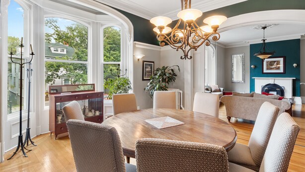 Un comedor con mesa de madera, sillas de mimbre y un candelabro.