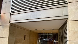 Ingresso di un edificio moderno con porta in vetro, cancello in metallo e pavimento piastrellato.