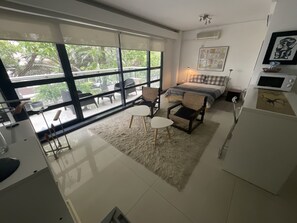 A modern bedroom with a large window, a bed, a desk, and a chair.