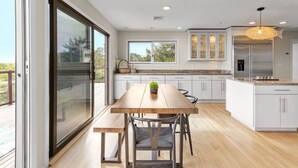Une cuisine moderne avec une table en bois, des armoires blanches et une grande fenêtre.