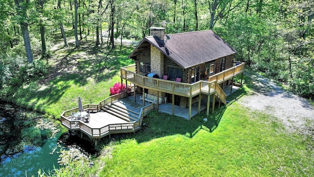 A log cabin with a deck, a covered outdoor seating area, and a pond. - Private Cabin with Pond on Family Farm (Belleville)