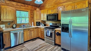 A spacious kitchen with wooden cabinets, stainless steel appliances, and a large refrigerator. - Private Cabin with Pond on Family Farm (Belleville)