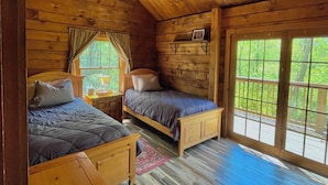A cabin with two wooden beds, a ceiling fan, and large windows. - Private Cabin with Pond on Family Farm (Belleville)