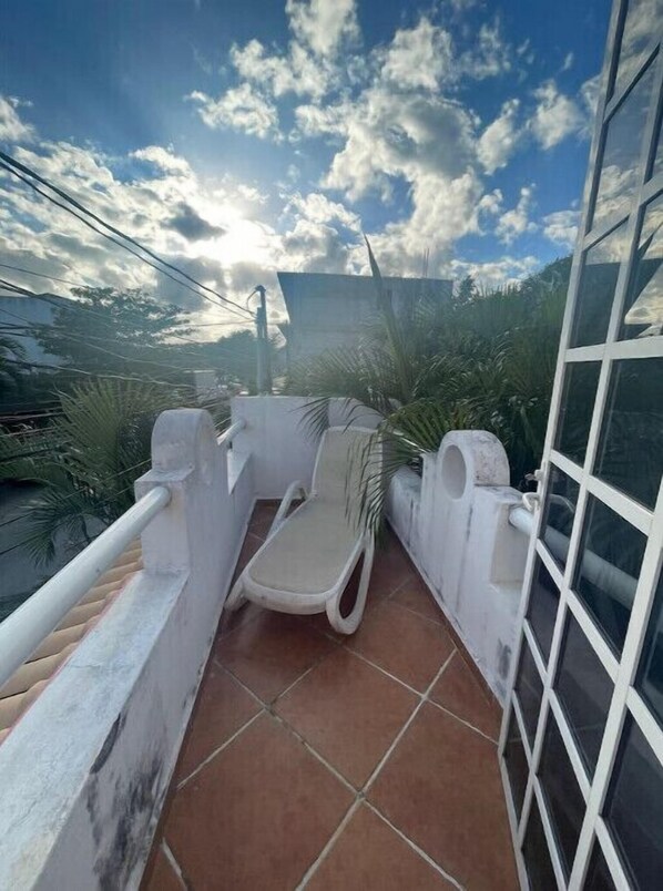 Enjoy a peaceful retreat on this balcony with a comfortable seating area and a view of the surrounding sky.
