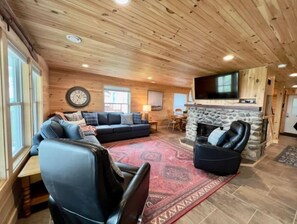 Cozy living room with a stone fireplace, comfortable seating, and a flat-screen TV.