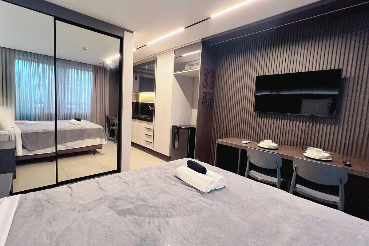 A hotel room with a bed, a desk, a TV, and a mirror.