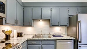 A modern kitchen with grey cabinets, stainless steel appliances, and a granite countertop. - North Charleston Vacation Rental Near Cooper River (North Charleston)