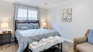 A bedroom with a bed, bedside lamps, a bedside table, a chair, and a wall-mounted artwork. - North Charleston Vacation Rental Near Cooper River (North Charleston)