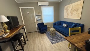 Una sala de estar con un sofá azul, una mesa de centro de madera, un televisor y una lámpara.