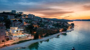 A coastal town with buildings along the waterfront, a swimming pool, and a boat in the water. - Beachfront Villa Milka with Pool (Okrug Gornji)
