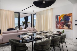 A modern dining area with a glass table, black chairs, and a large abstract painting on the wall.