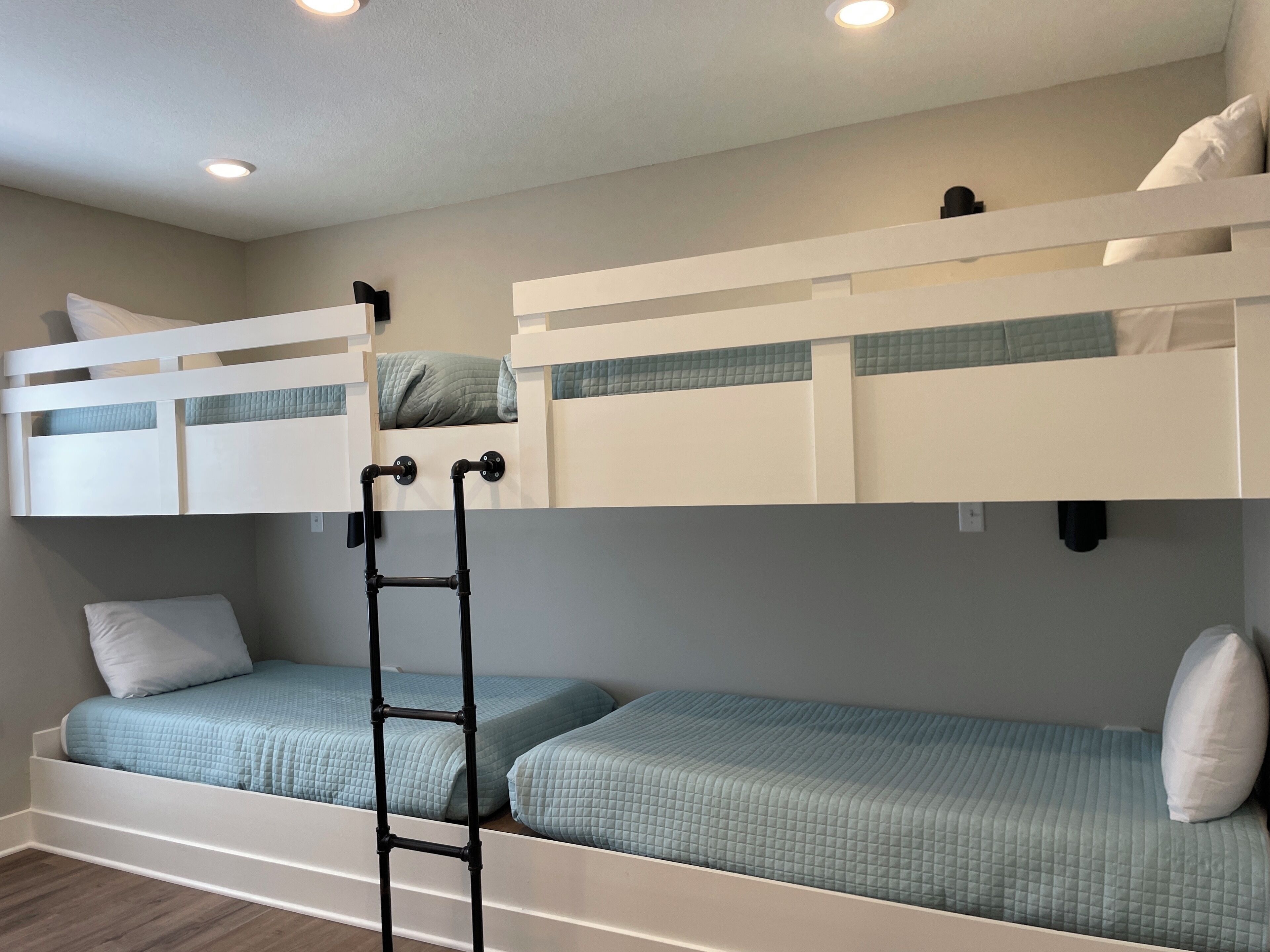 Une chambre avec un lit superposé, une échelle, un lit inférieur et une tête de lit.
