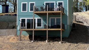 A two-story house with a balcony, multiple windows, and a gravel driveway. - Lake Escape at Station 46 (Gravois Mills)