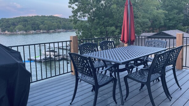 A deck with a table and chairs, overlooking a body of water with boats docked. - Waters Edge at Station 46 (Gravois Mills)
