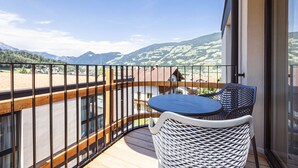 Een balkon met een tafel en stoelen, met uitzicht op een bergachtig landschap.