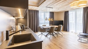 A modern kitchen with a built-in stove, a sink, and a dining area with a table and chairs. - Superior Apartment with 2 bedrooms (Fügen)