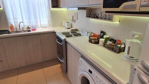 A compact kitchen with a washing machine, a microwave, and a toaster. - Apartamento Hermoso y muy Cómodo (Ushuaia)