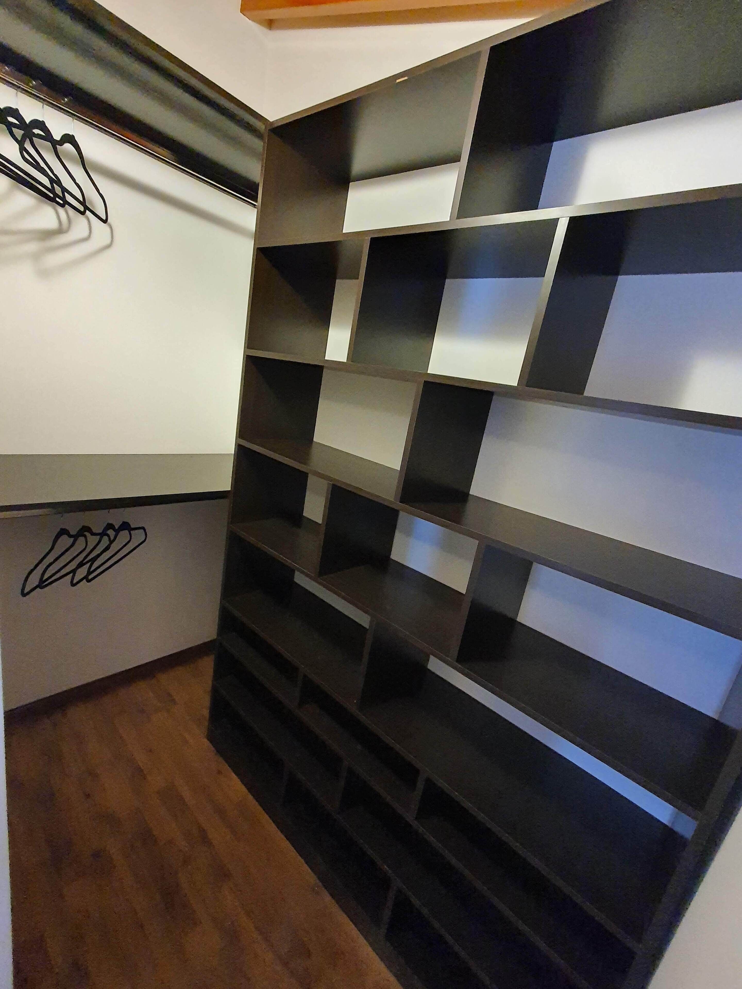 Ein Zimmer mit Wandgestaltung in Schwarz und Weiß Schachbrettmuster, Holzboden und weißer Wand mit einem schwarzen Logo.