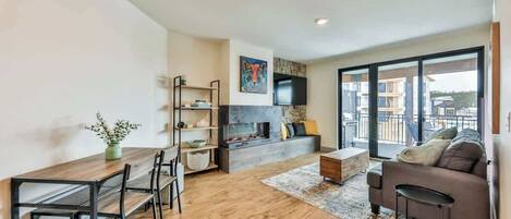 A modern living room with a dining area, a fireplace, a sofa, and a TV.